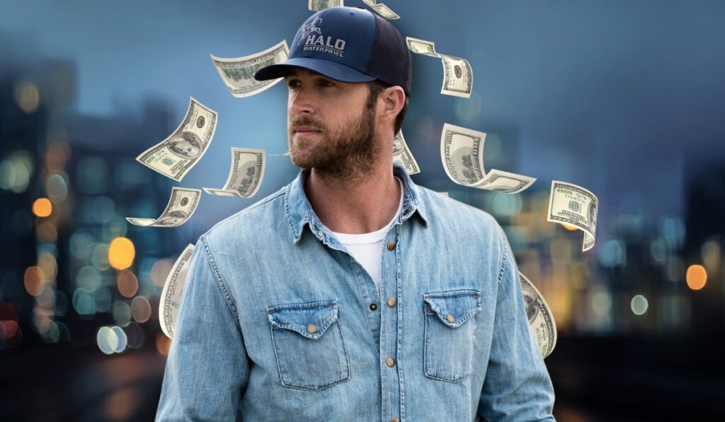 Riley Green in a denim shirt and cap with dollar bills floating around him