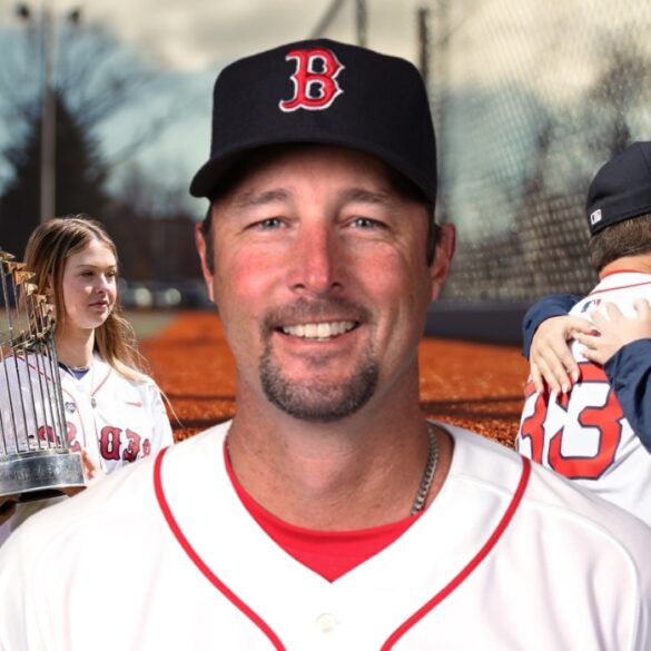 Baseball player in a Red Sox uniform smiling, with family and a championship trophy in the background