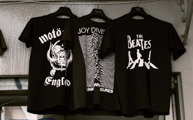 Black shirts of famous bands hanging on the wall