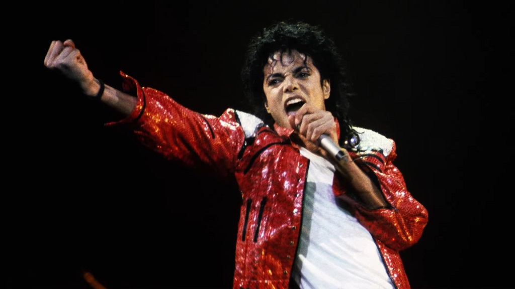 Michael Jackson in a red sequined jacket singing passionately on stage