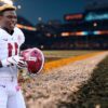 Henry Ruggs in an Alabama football uniform holding his helmet on the sideline of a stadium