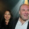 Actor James Gandolfini smiling in a suit with his wife Deborah Lin standing beside him at an event, illuminated by stage lights