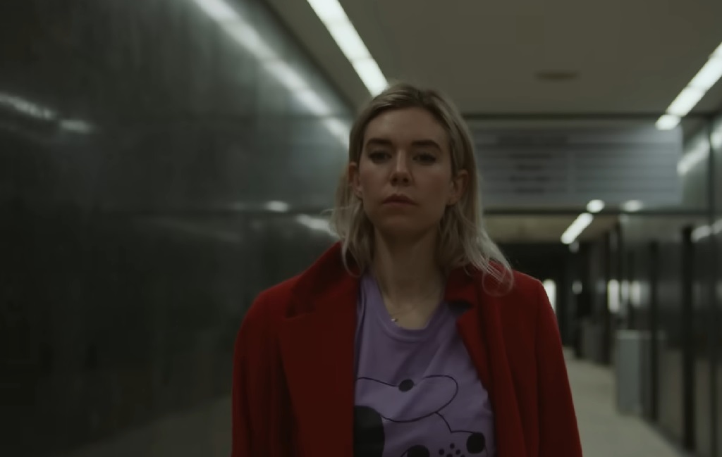 The Many Faces of Vanessa Kirby: Princess Margaret, Grieving Mother in Pieces of a Woman, and Marvel Icon Vanessa Kirby as Martha in Pieces of a Woman, walking through a sterile hallway in a red coat and purple shirt, her face calm but distant.