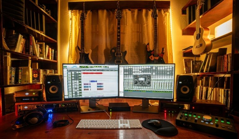 Home music studio setup with dual monitors, guitars, and mixing gear used with free VST plugins for rock production