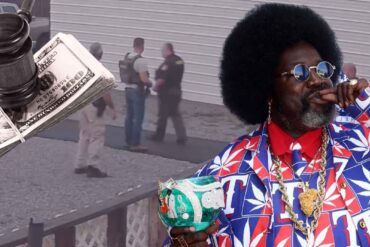 Afroman holding a decorated cup with police scene and money imagery in the background