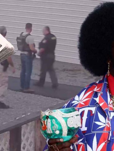 Afroman holding a decorated cup with police scene and money imagery in the background