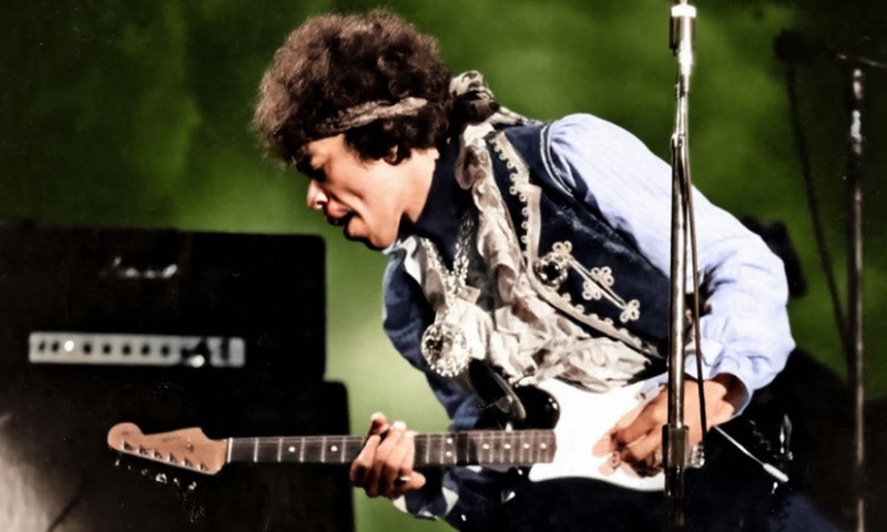 The Bandana in Rock Culture: 10 Iconic Moments That Defined a Generation Jimi Hendrix energetically plays an electric guitar on stage, wearing a blue and white outfit with a headband