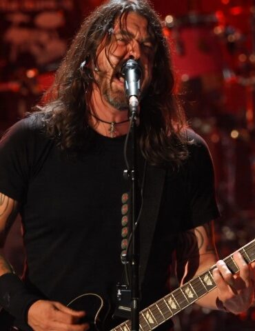 Dave Grohl passionately performs on stage, singing into a mic