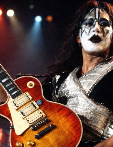 The Life and Career of Ace Frehley, the Guitarist Who Helped Shape the Sound of KISS A musician with dramatic black-and-white face paint and a shiny, silver costume plays an electric guitar on stage