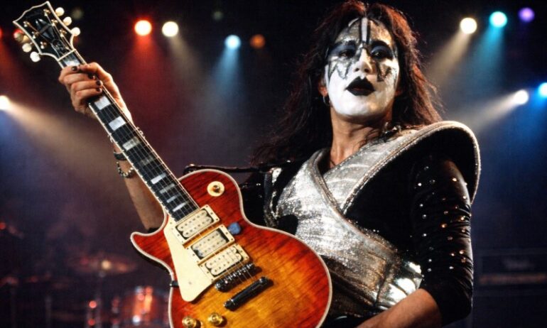 The Life and Career of Ace Frehley, the Guitarist Who Helped Shape the Sound of KISS A musician with dramatic black-and-white face paint and a shiny, silver costume plays an electric guitar on stage