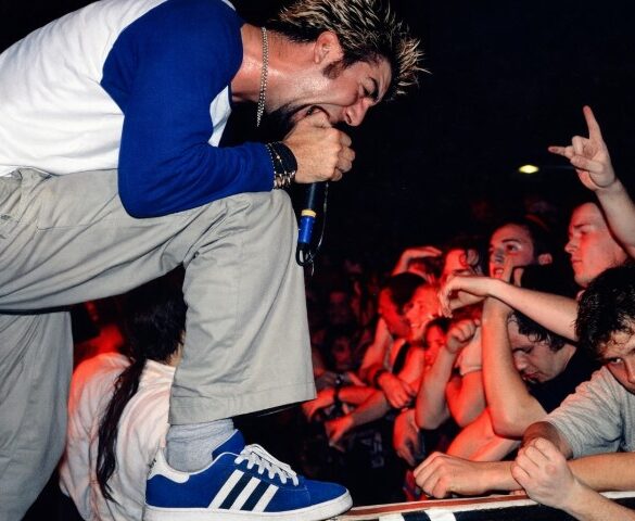 The Athlete-Rocker Crossover: When Sports Gear Became Rock Fashion A male performer with spiky hair passionately sings into a microphone at a concert, leaning toward an enthusiastic crowd