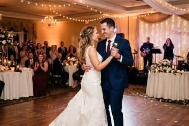 Best Songs For A Modern Wedding: Music Ideas Guests Will Enjoy A bride in a lace gown and groom in a navy suit share a joyful first dance