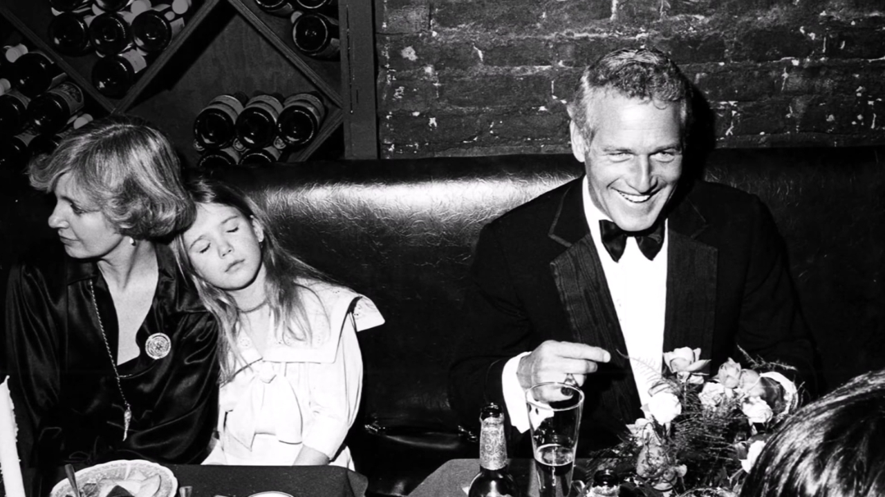 Jackie Witte’s Cause of Death - How Did Paul Newman’s First Wife Die? A man in a tuxedo smiles at a table beside a woman and a young girl