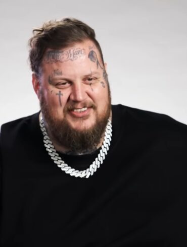 Jelly Roll Bio - Age, Family, Marriage and Fame Jelly Roll smiles in a black shirt with a silver chain against a plain gray backdrop