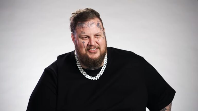 Jelly Roll Bio - Age, Family, Marriage and Fame Jelly Roll smiles in a black shirt with a silver chain against a plain gray backdrop