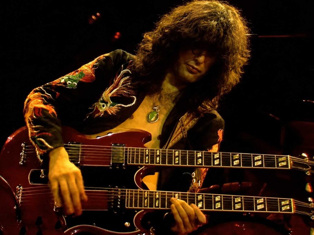 10 Rock and Metal Bands Inspired by Fantasy Books Rock guitarist playing a red double-neck electric guitar during a live concert.