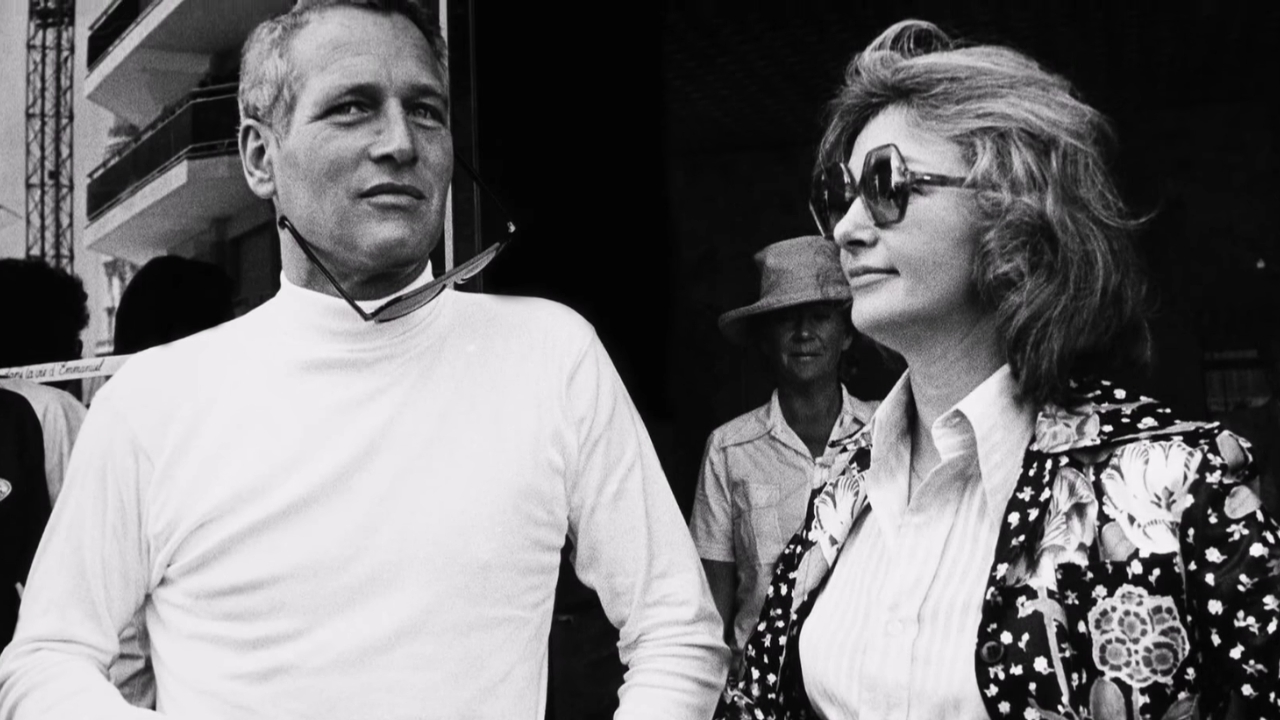 Jackie Witte’s Cause of Death - How Did Paul Newman’s First Wife Die? A man in a white shirt stands beside a woman in dark glasses and a floral jacket