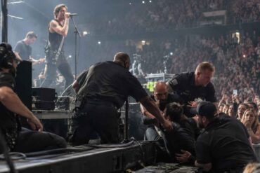 Behind-the-Scenes -Security guards removing an intruder from the stage during a crowded rock concert.