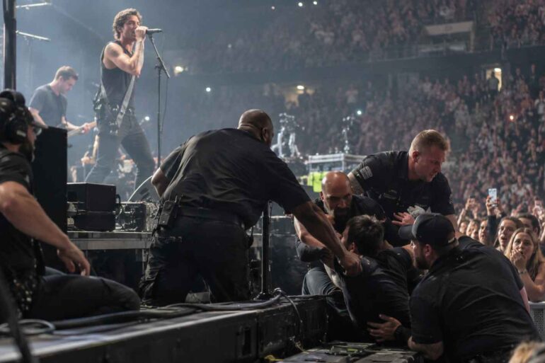 7 Crazy Behind-the-Scenes Moments That Happened During Live Concerts Behind-the-Scenes -Security guards removing an intruder from the stage during a crowded rock concert.