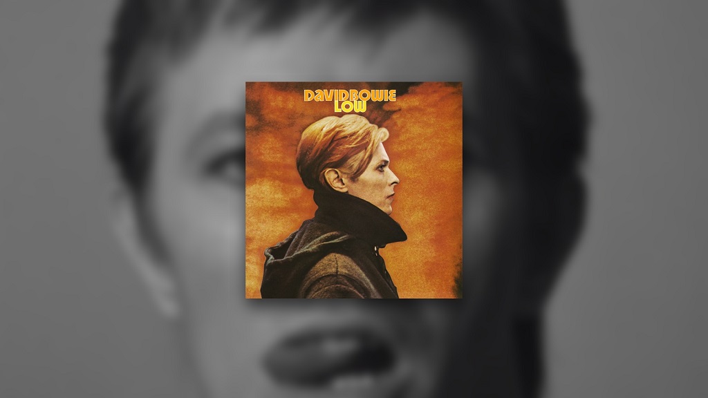 10 Classic Rock Albums Everyone Hated Before They Became Cult Classics David Bowie’s Low album cover over a blurred black-and-white portrait of Bowie.