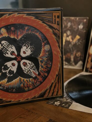 KISS vinyl record and memorabilia displayed on a wooden table.