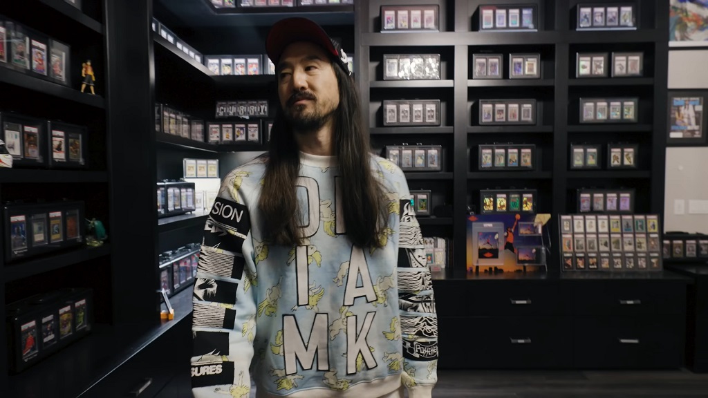 There Is Much More to Steve Aoki Than Music and Flying Cakes Steve Aoki standing in front of his trading card collection