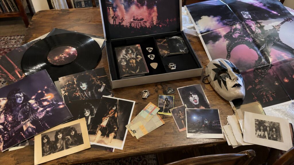 KISS vinyl, photos and memorabilia spread across a wooden table.