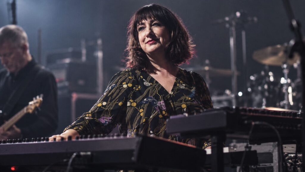 Gillian Gilbert performing at a keyboard during a New Order show.