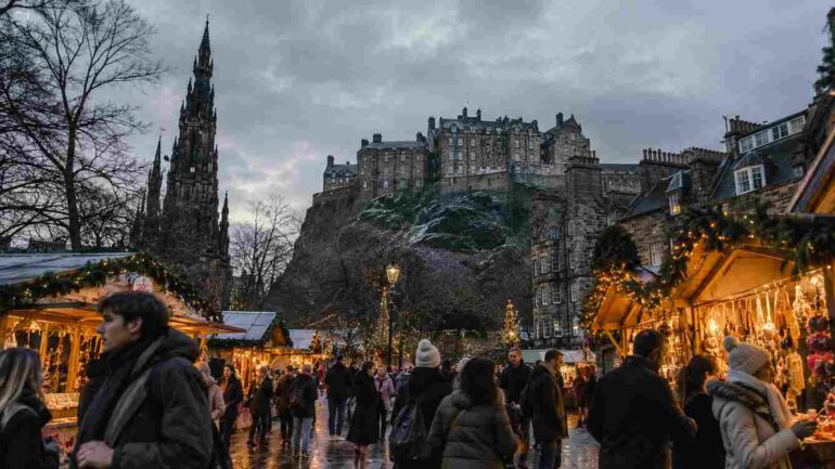 Scotland During Christmas - Christmas market in Edinburgh with festive stalls, winter crowds and Edinburgh Castle in the background.