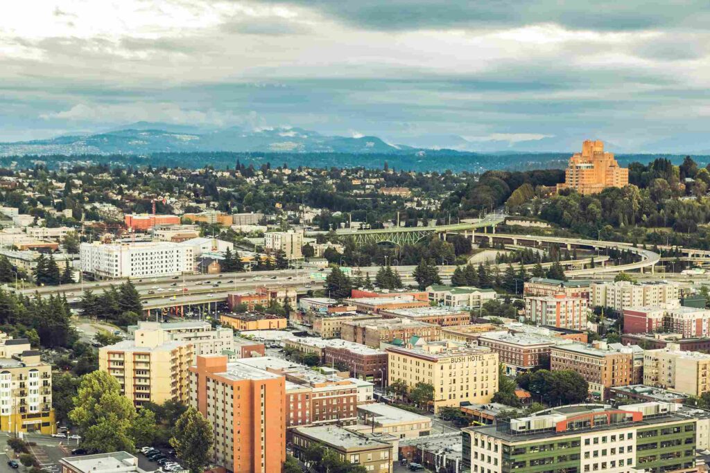 Seattle Housing Market 2026, Is Now a Better Time to Buy a House? Aerial view of Seattle neighborhoods, residential buildings, highways, and surrounding hills.